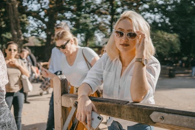 Wearing a white long sleeve shirt, wearing sunglasses woman sitting on a bench
